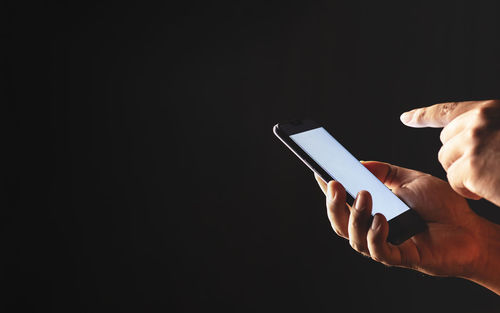 Low angle view of person using mobile phone against black background