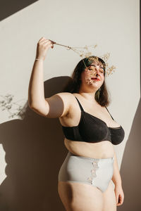 Portrait of young woman standing against wall