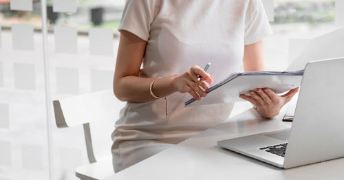 Midsection of man using mobile phone while sitting on table