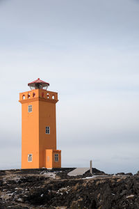 Lighthouse by sea against sky