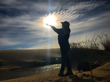 Silhouette man standing against sun during sunset