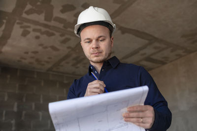 Portrait of young man standing against wall