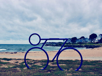 Bicycle wheel on beach against sky in park