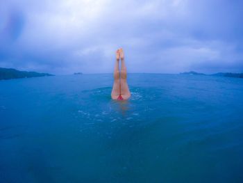 Low section of woman on sea against sky