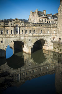 Reflection of arch bridge and buildings against sky