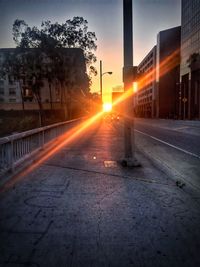 Road passing through city during sunset