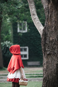 Rear view of woman against tree trunk