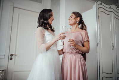 Bridesmaid and bride holding champagne flute