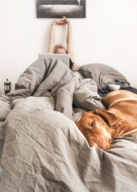 Low section of man relaxing on bed at home