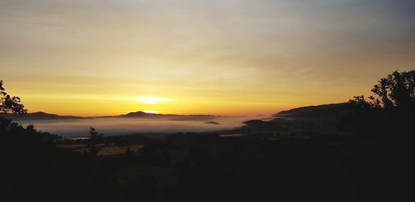 Scenic view of silhouette mountains against orange sky