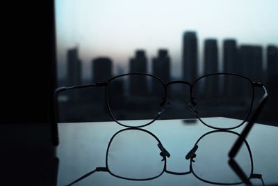 Close-up of eyeglasses against buildings in city