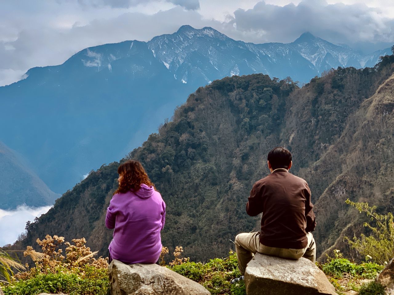 mountain, rear view, mountain range, real people, leisure activity, beauty in nature, sitting, scenics - nature, lifestyles, women, two people, nature, sky, tranquil scene, tranquility, adult, togetherness, people, vacations, trip, looking at view, outdoors, mountain peak, couple - relationship