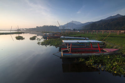 Boat moored on lake against sky