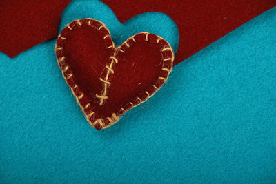 Close-up of felt craft heart over blue background