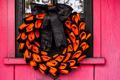 Orange and black craft wreath halloween decoration on vintage pink wooden door