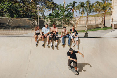 Friends looking at man skateboarding on sports ramp