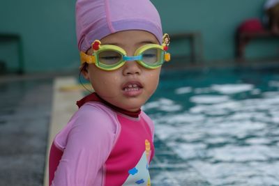 Cute girl wearing swimming goggles by pool