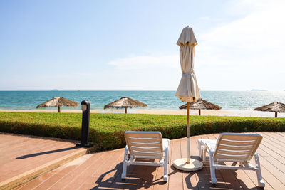 Chairs and table at beach against sky