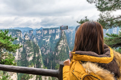 Woman photographing cliff through mobile phone