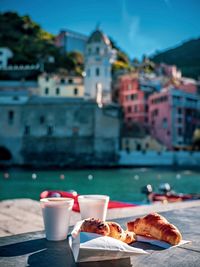 Croissant with coffee on table against buildings in city