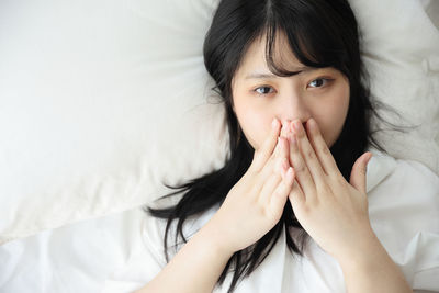 Portrait of young woman looking away while lying on bed at home