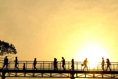 Silhouette people by sea against sky during sunset
