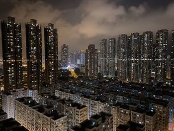 Illuminated modern buildings in city against sky at night