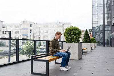 Man working on laptop sitting on business center bench