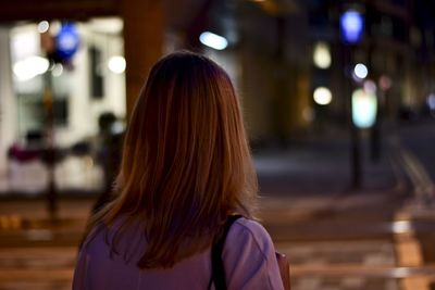 Rear view of woman standing in city at night
