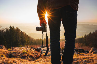 Photographer with camera in sunset taking photos of landscape. 