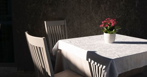 Flowers in vase on table by chairs