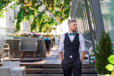 Waiter standing with hands in pockets at restaurant