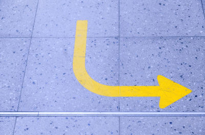 High angle view of yellow arrow symbol on footpath