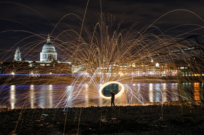 Man with wire wool standing at riverbank against st pauls cathedral