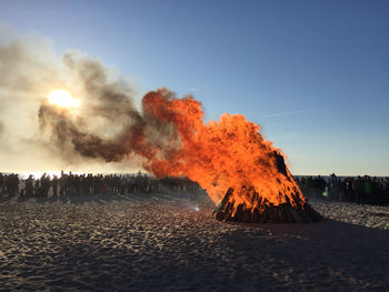 Group of people around fire at beach against sky