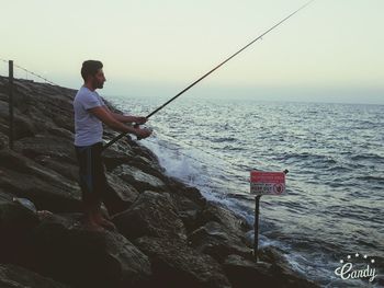 Rear view of boy fishing on beach