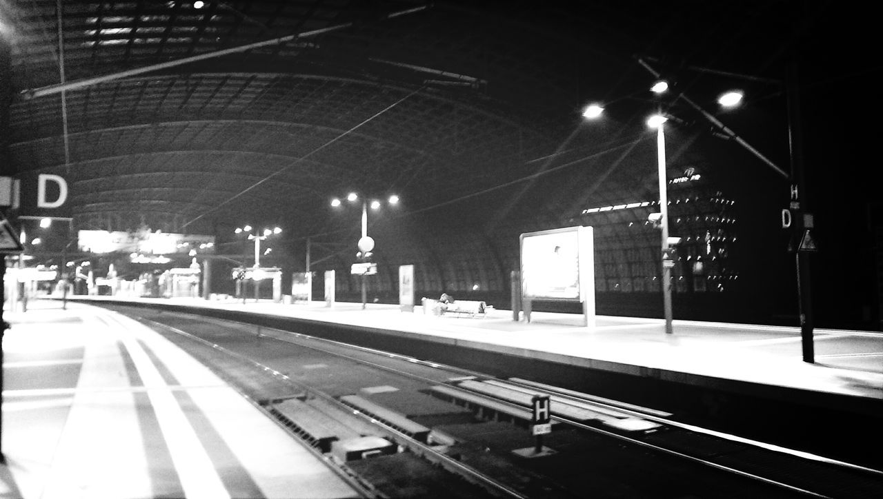 transportation, illuminated, railroad track, railroad station platform, railroad station, public transportation, night, the way forward, rail transportation, built structure, mode of transport, architecture, lighting equipment, travel, street light, diminishing perspective, city, road, train - vehicle, vanishing point