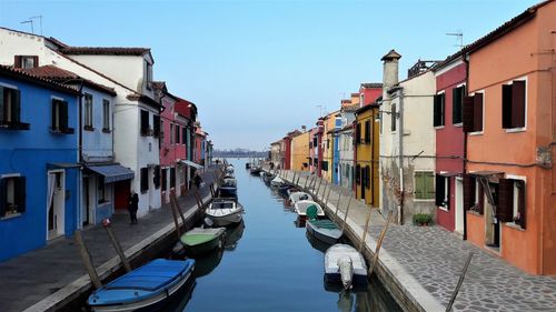 Boats moored in canal against clear sky