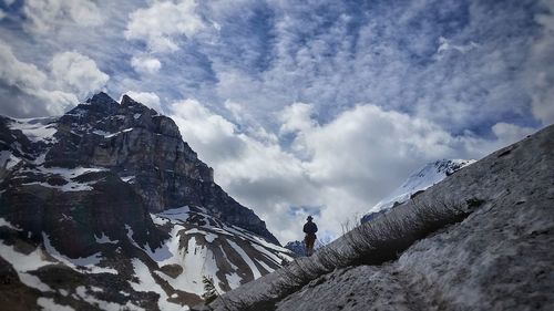 Low angle view of man standing on rock against sky