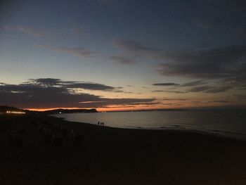 Scenic view of beach against sky at sunset