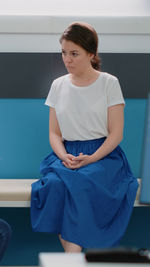 Side view of young woman sitting on railing