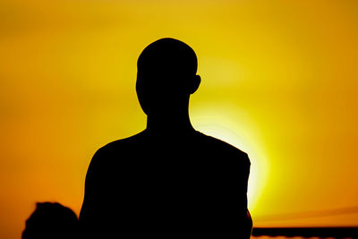 Rear view of silhouette man standing against orange sky