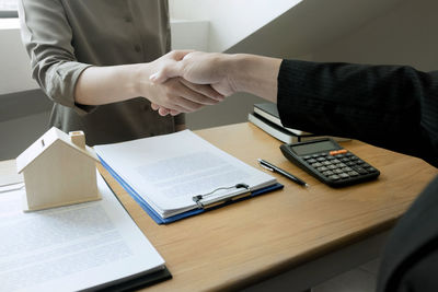 Midsection of man and woman reading book on table