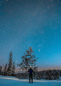 Full length of woman standing on snow field against sky at night