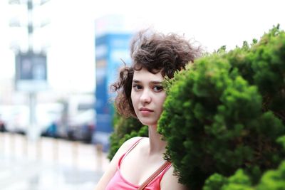 Portrait of beautiful young woman standing by plants