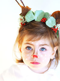 Close-up portrait of cute girl with painted face against white background