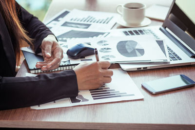 Cropped hands of businessman using laptop at desk in office