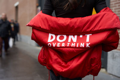 Rear view of woman wearing jacket with text outdoors