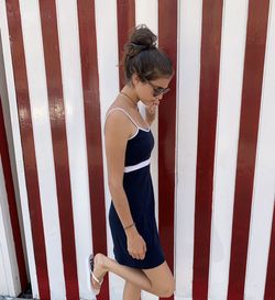 Side view of young woman standing by railing