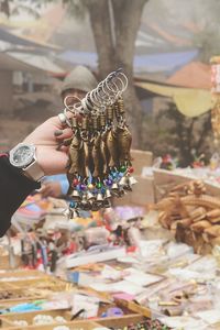Cropped hand of man holding key rings at market stall